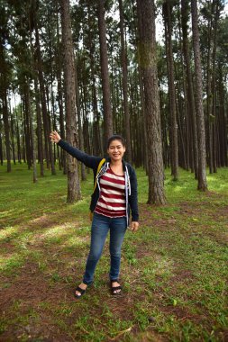 Gülümseyen Asyalı kadın çam ormanında poz veriyor 