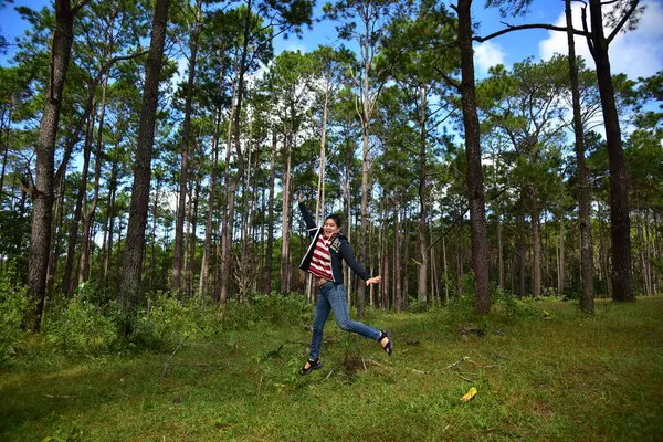 Mutlu Asyalı kadın çam ormanında atlıyor. 