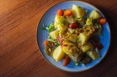 Lezzetli haşlanmış patatesler, canlı vişneli domatesler, dilimlenmiş acı biberler ve taze taze taze soğanlarla süslenir. Bu canlı yemekle duyular için bir ziyafet bekliyor..