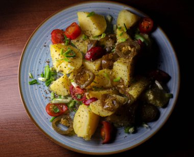 Haşlanmış patatesler, acı biber dilimleri, taze vişne domatesleri ve taze doğranmış taze soğanlarla ustalıkla baharatlandırılır ve lezzetle patlayan canlı bir tabak oluşturulur..