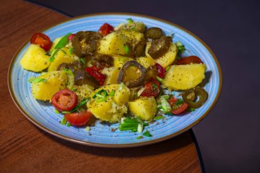 Lezzetli bir tabak haşlanmış patates acı biber, sulu vişneli domates ve taze doğranmış taze soğanla süslenir. Renkli karışım sıcaklık ve lezzet getirir, her yemek için mükemmeldir..