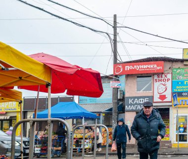 Kyiv, Ukrayna - 2 Mart 2025. İnsanlar canlı bir pazarda renkli tezgahlarda koştururken, satıcılar hafif kar yağışı ortasında taze ürünler ve sıcak konforlu gıdaları teşvik ediyorlar..