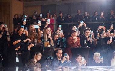 Kyiv, Ukrayna - 17 Şubat 2025. Katılımcılar Gasanova moda gösterisini hevesle izliyorlar. İnsanlar, ekrandaki çarpıcı tasarımları belgelemek için cihazlarını kullanarak podyuma odaklanmış durumdalar..