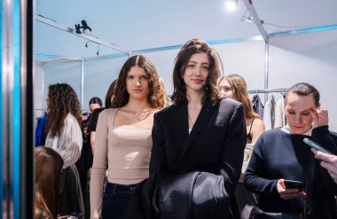 Kyiv, Ukrayna - 14 Şubat 2025: Podyumdan dakikalar önce, modeller sohbet ederken, saçlarını kestirirken ve Ukrayna Moda Haftası 'nda kulis kıyafetlerini ayarlarken görülüyorlar..