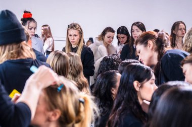 Kyiv, Ukrayna - 14 Şubat 2025: Ukrayna Moda Haftası 'nın hareketli kulisinde modeller, tasarımcılar hareketli bir etkinlik ortamında görünüşlerini tamamlarken makyaj ve saç şekillendirme ile hazırlanıyorlar..