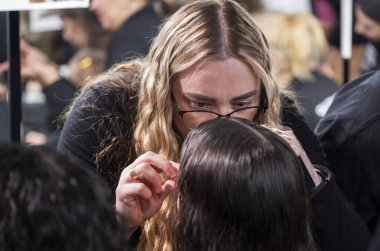 Kyiv, Ukrayna - 14 Şubat 2025: Enerji tasarımcıları ve stilistler podyum için modeller hazırlayın, makyaj, saç ve kıyafetlerde ince ayar yapın, heyecan ve beklenti yaratın.