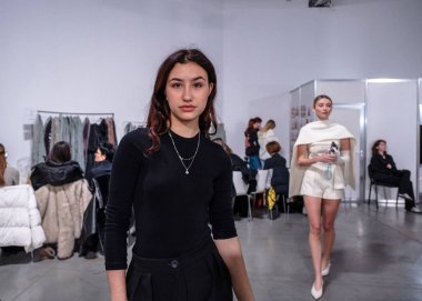 Kyiv, Ukrayna - 14 Şubat 2025: Model sohbetleri ve sahne arkasında hazırlıklar yoğunlaşırken hızlı pozlar vermek. Tasarımcılar kıyafetleri düzeltirken stilistler de mükemmel saç ve makyaj yapar..