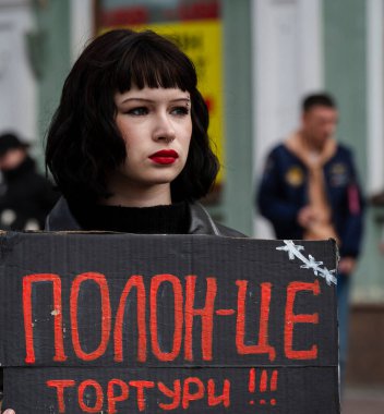 Kyiv, Ukrayna - 30 Mart 2025: Özgür Azov mitinginde kararlı bir şekilde duran genç bir kadın, hareketli bir şehrin arka planına karşı cesur bir tabela tutuyor ve çatışmalardan etkilenenleri savunuyor.