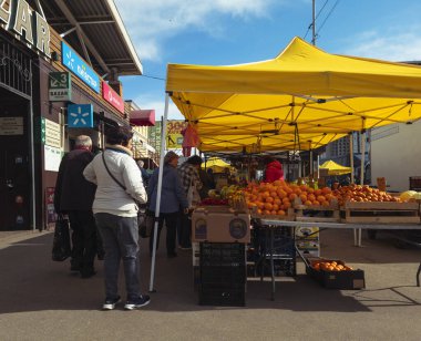 Kyiv, Ukrayna - 2 Nisan 2025: Yerel halk Lisova sokak pazarında gezerken ve sosyalleşirken, satıcılar açık hava kentsel yaşamın canlı atmosferinin keyfini çıkarırken parlak sarı çadırların altında taze ürünler sergiliyorlar.