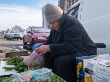Kyiv, Ukrayna - 2 Nisan 2025: Lisova sokak pazarında, bir satıcı yerli halk ve ziyaretçiler canlı alışverişler yaparken taze yeşil otları dikkatle inceler.