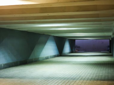 Işık ve gölgeler, geceleri boş ve aydınlık bir yeraltı geçidinde geometrik şekiller oluşturmak için iç içe geçerek kentsel çevrede ürkütücü ve gizemli bir atmosfer yaratırlar.