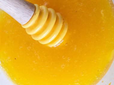 Bal toplayıcısının yakın plan görüntüsü, cam bir kaseye altın bal damlatan, kahvaltıya veya çaya tatlı bir dokunuş katan, doğal aromalı aşçılık kreasyonlarını geliştiren