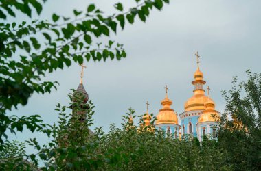 Ukrayna 'nın başkenti Kyiv' de bulunan yeşil ağaçların arkasında altın kubbeler parıldıyor ve doğa ile mimariyi harmanlayan pitoresk bir manzara yaratıyor.
