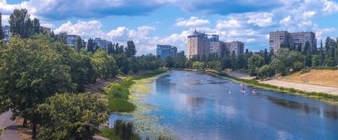 Güneşli bir yaz gününde Svislach Nehri 'nde kürek çeken sporcuların yer aldığı panoramik manzara kent mimarisi ve doğayı ön plana çıkarıyor.