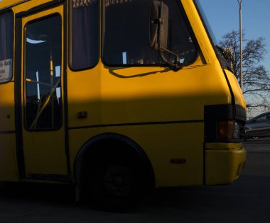 Kyiv, Ukrayna - 20 Mart 2025: Sarı toplu taşıma otobüsü gün batımında şehirde bekliyor.