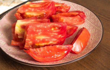 Tuz ve biberle tatlandırılmış kabuklu domatesler pembe bir tabakta, sağlıklı bir aperatif olarak kullanılmaya ya da çeşitli yemeklerde malzeme olarak kullanılmaya hazırdır.