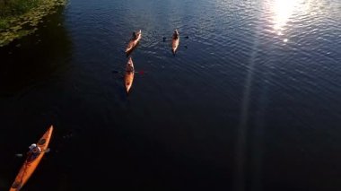 Kayakçılar sakin su yüzeyinde kürek çekerek, sıcak güneş ışığının tadını çıkararak, dışarıda sakin bir zaman ve doğa ile iletişim anı yaratıyorlar.