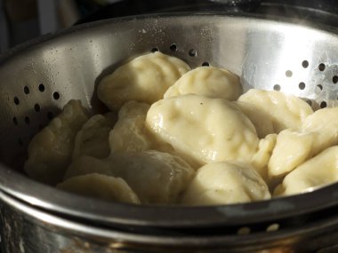 Taze pişmiş hamur köfteleri kaynatıldıktan sonra metal bir kevgire buharlanıyor, tereyağı, ekşi krema veya diğer malzemelerle servis edilmeye hazır hale getiriliyor.