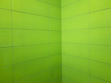 Yeşil dikdörtgen seramik fayanslar canlı ve modern bir görünüm yaratıyor, banyo duvarının köşesini kaplıyor, temiz ve su geçirmez bir yüzey sağlıyor.
