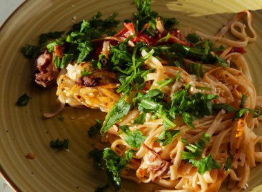 Taze ördek eti, taze roka, susam tohumu ve zengin domates sosu içeren nefis ev yapımı makarna tabağı, iştah açıcı bir mutfak deneyimi yaratıyor.