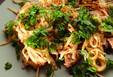 Et, roka, susam tohumu ve diğer baharatlarla tatlandırılmış lezzetli ev yapımı makarna lezzetli ve görsel olarak çekici bir mutfak deneyimi yaratıyor.