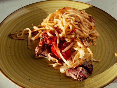 Lezzetli et ve domates sosuyla kaplanmış erişteler canlı yeşil bir tabağın üzerinde oturup öğle veya akşam yemeği için mükemmel ama tatmin edici ev yapımı basit bir yemek sunuyorlar.