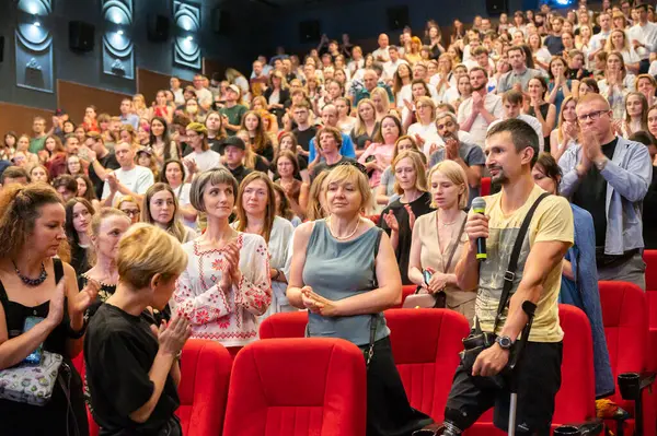 Kyiv, Ukrayna, 31 Ağustos 2025. Seyirci, yönetmenle konuşurken protez bacaklı ve koltuk değnekli bir Ukraynalı gaziyi alkışlıyor.