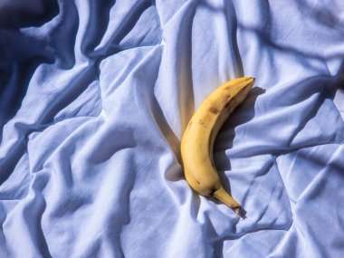 Yumuşak mavi yatak çarşaflarında dinlenen taze muz, sabah güneşiyle yıkanmış, dingin ve davetkar bir atmosfer yaratıyor rahatlama ve refah için mükemmel.