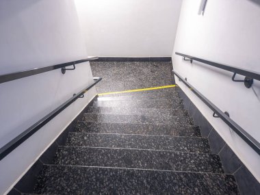Modern granit merdiven aşağı iniyor. Sarı dokunmatik asfalt kör ve görme engelli insanlar için ve kamu binasındaki metal tırabzanlar için.