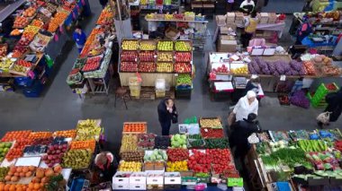 Kyiv, Ukraine - 10th April, 2025:  Colorful stalls at an indoor farmers market full of fresh fruits and vegetables with customers browsing and buying local food, creating a vibrant and bustling scene from an aerial perspective