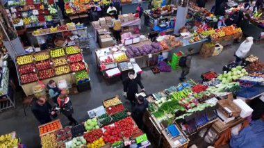 Kyiv, Ukraine - 10th April, 2025: High angle view of a bustling indoor market with people shopping for fresh fruit and vegetables displayed on numerous stalls, highlighting a vibrant community commerce and healthy food selection