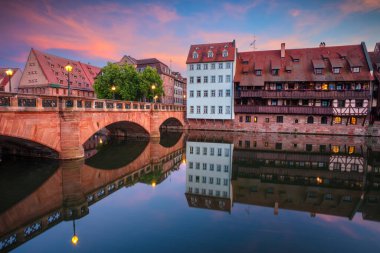 Nuremberg, Almanya. Günbatımında Pegnitz Nehri 'ndeki Max Köprüsü ve ufuk çizgisinin yansımasıyla Almanya' nın eski Nuremberg kentinin şehir manzarası.