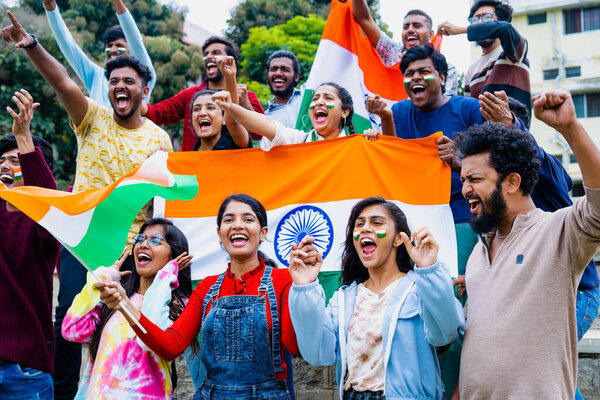 Group of audience at stadium shouting, screaming for win by holding indian flags while watching crcket sports match at stadium - concept of entertainment, championship tournament and entertainment.