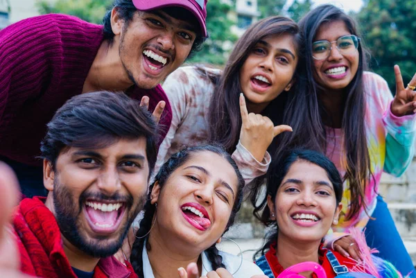 Group of cheerful excited young happy friends with taking selfie by holding camera during at college - concept of friendship, social media and togetherness.