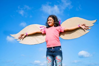 Mavi gökyüzüne karşı uçmaya çalışan yapay kanatlı mutlu çocuk - özgürlük kavramı, bağımsız ve rüya gibi.