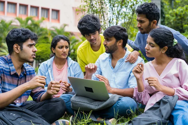 Group of college students discussing about project with team leader from laptop at college campus - concept of teamwork, ideas and collaboration.
