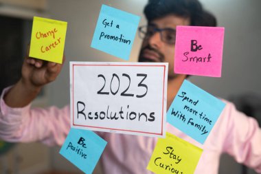2023 Kararları yapıştıran genç adam ofiste yapışkan notlar kullanıyor - yeni yıla hazırlık ve hedef belirleme kavramı.