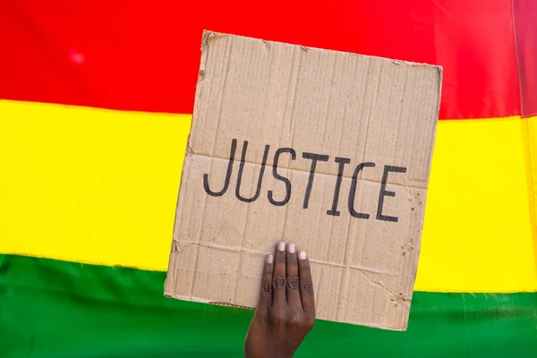 Close up shot of showing justice sign board in front of black history month flag - concept of activism, unity and freedom