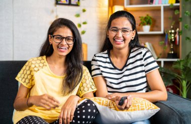 happy siblings laughing while watching comedy show or movie on tv or television - concept of relaxation, weekend entertainment and living streaming