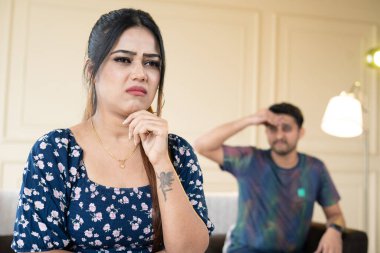 Irritated wife while talking with angry husband at home on couch - concpet of couple conflcit, family problems and break up.