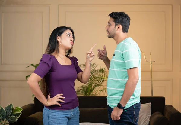 focus on girl, Angry indian couple fighting by shouting eachother while standing at home - conept of relationship problems, conflict and disagreement