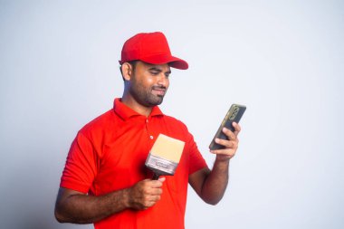 Mutlu ressam inşaat alanında fırça tutarak cep telefonu kullanmakla meşgul - sosyal medya, teknoloji ve rahatlama kavramı.