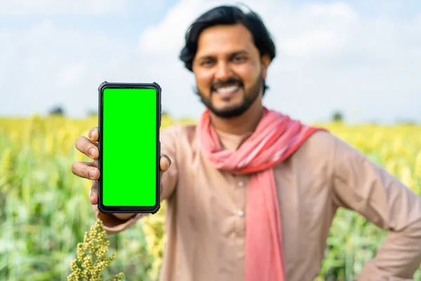 stock image Focus on smartphone, Happy farmer showing green screen mobile phone by looking camera at farmland - concept of app promotion, advertisement and agriculture