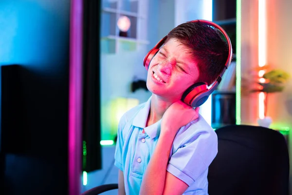 stock image exhausted teenager kid suffering from neck pain due to over playing of video game on computer - concept of health care, game addiction and tiredness