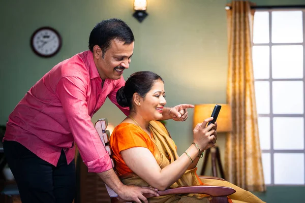 快乐微笑的夫妻在家检查手机 沟通和网上购物的概念 — 图库照片