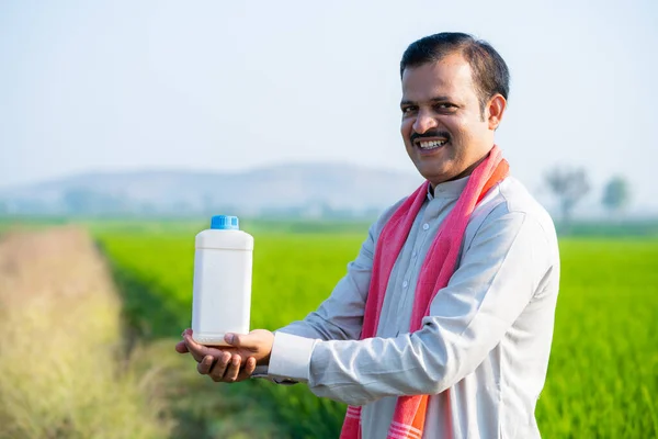 Счастливый Индийский Сельский Фермер Держит Бутылку Удобрений Глядя Камеру Сельхозугодий — стоковое фото
