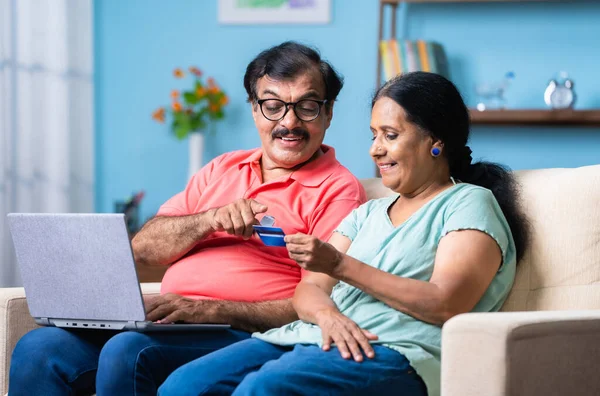 印度老年夫妇坐在沙发上在家用信用卡网上支付或购物 安全银行 电子商务和团结的概念 — 图库照片