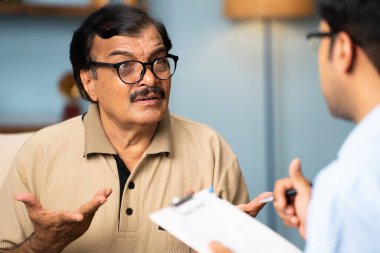 Hintli bankacı evde para vererek yaşlı kadından imza alıyor - finansal yardım, yatırım ve emeklilik maaşı kavramı.