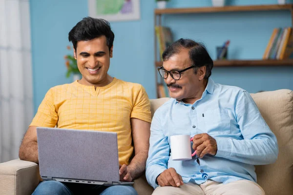 印度成年人在家里喝茶或喝咖啡时用笔记本电脑开心的儿子 周末度假 恋爱和放松的概念 — 图库照片