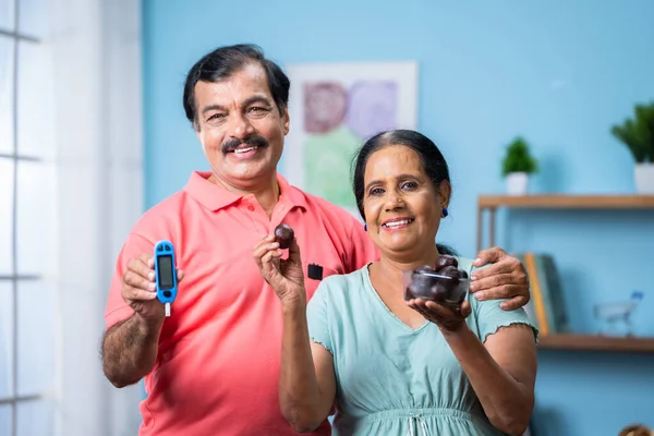 快乐的印度老年夫妇通过在家里看相机来展示糖蜜糖 糖尿病的概念 健康的生活方式和医疗 — 图库照片
